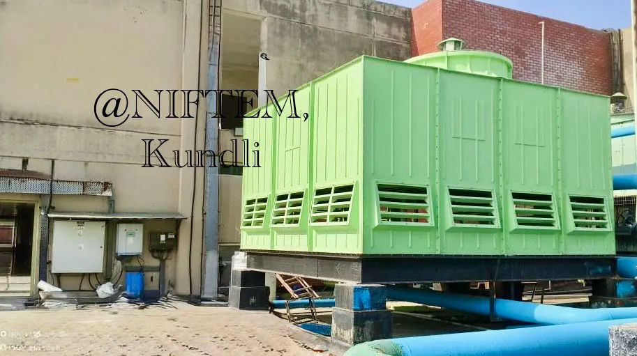 Green multi-cell FRP cooling tower with blue header piping at NIFTEM Kundli