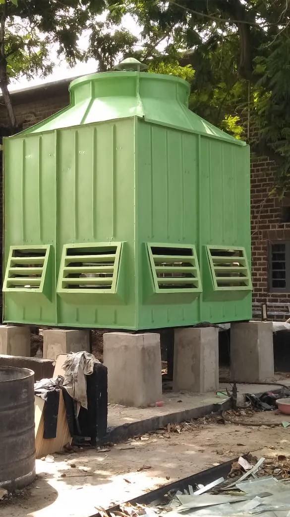 Green square FRP cooling tower raised on concrete pedestals with louvred air inlets